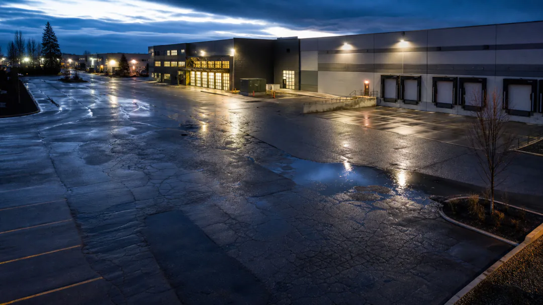 Wet commercial pavement with cracking, patch transitions and a ponding area